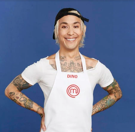 Dino Angelo Luciano smiling in a MasterChef apron against a blue background